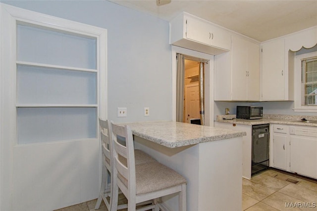 kitchen with dishwasher, a breakfast bar area, light countertops, light tile patterned flooring, and white cabinets