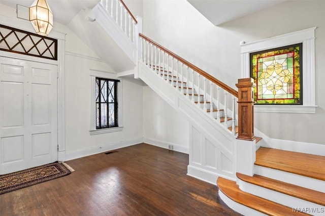 foyer entrance featuring stairway, baseboards, visible vents, and wood finished floors