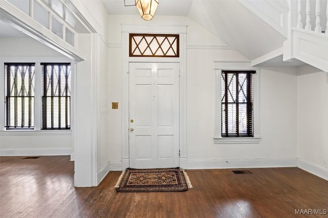 foyer entrance with dark wood finished floors, baseboards, and visible vents