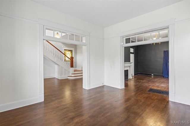 unfurnished room with stairway, a fireplace with flush hearth, baseboards, and wood finished floors