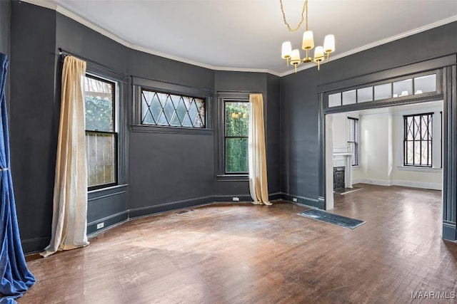 unfurnished dining area with baseboards, a chandelier, a fireplace with flush hearth, ornamental molding, and wood finished floors