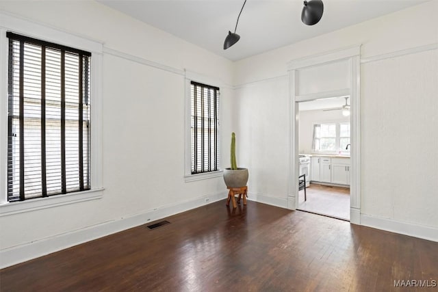 unfurnished room featuring a sink, visible vents, baseboards, and wood finished floors