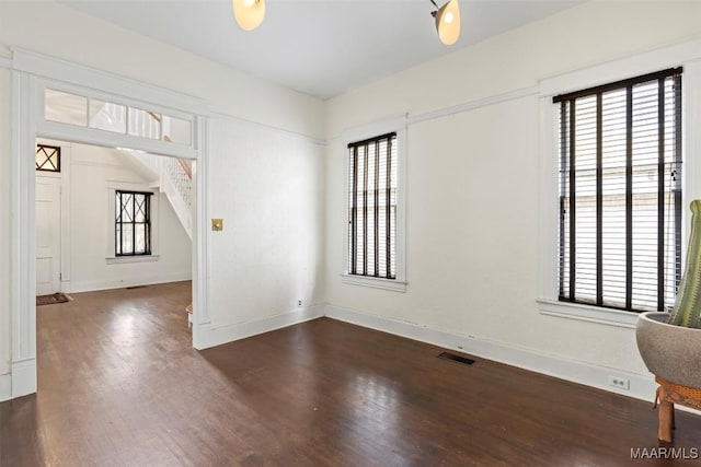 empty room with visible vents, baseboards, and wood finished floors