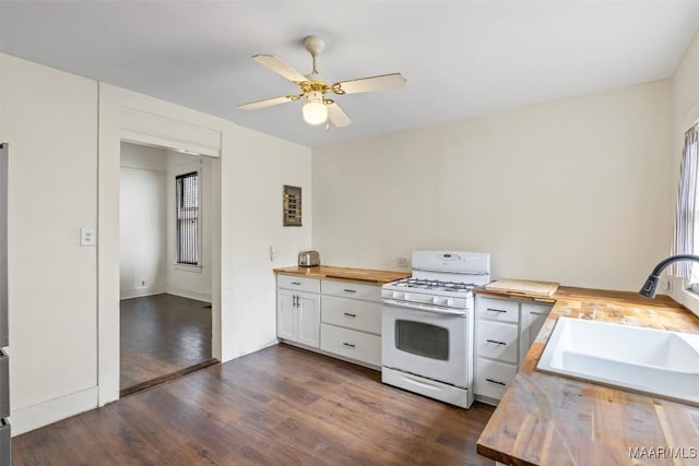 kitchen featuring a sink, white cabinetry, butcher block counters, white gas range, and dark wood-style flooring