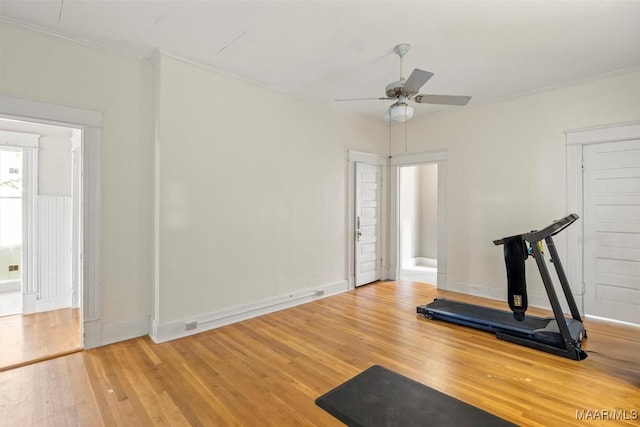 exercise area with crown molding, wood finished floors, baseboards, and ceiling fan