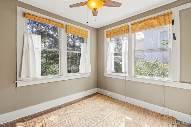 empty room featuring a ceiling fan and baseboards