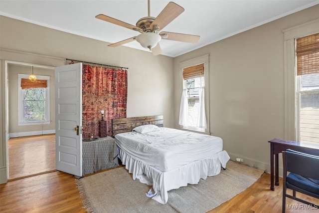 bedroom featuring baseboards, multiple windows, and light wood-style flooring