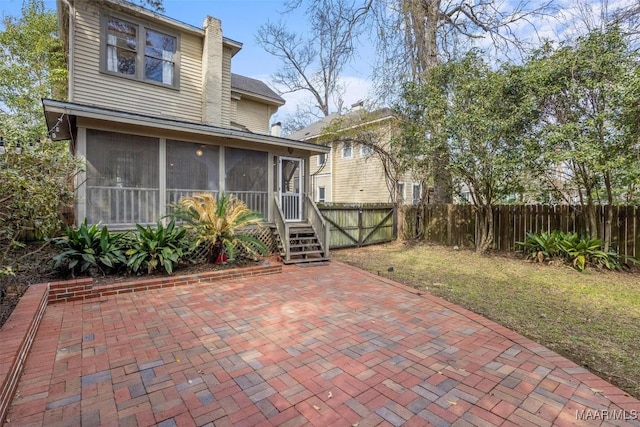 back of property featuring a lawn, a patio, a fenced backyard, a sunroom, and a chimney