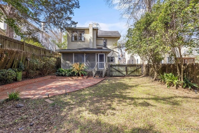 back of property with a patio, a gate, a yard, a fenced backyard, and a sunroom