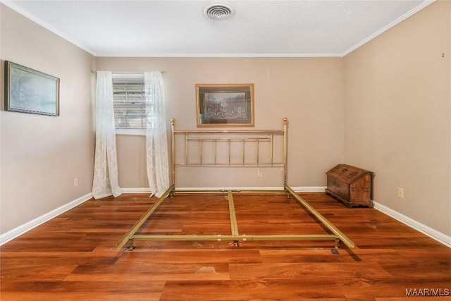 interior space featuring visible vents, baseboards, wood finished floors, and ornamental molding