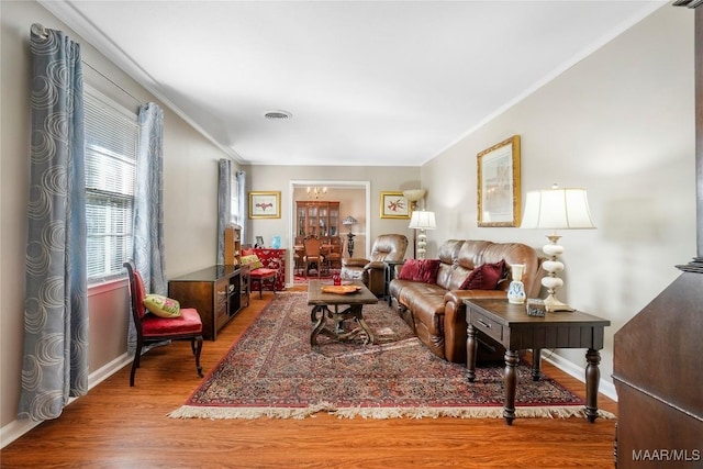 living room with visible vents, baseboards, wood finished floors, and ornamental molding