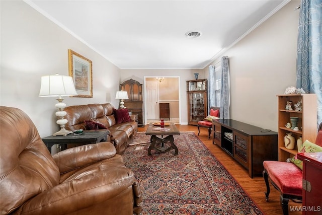 living area with visible vents, crown molding, and wood finished floors