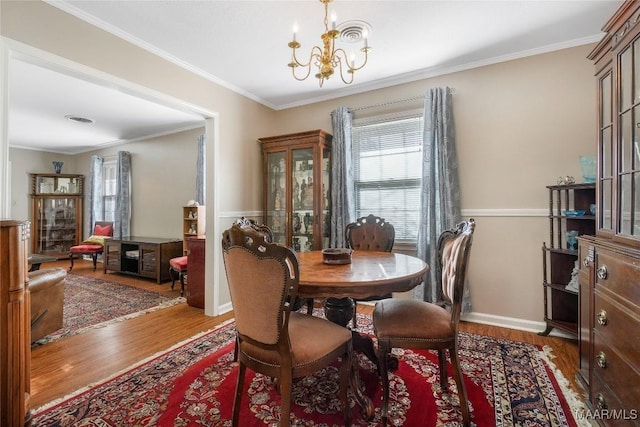 dining area with visible vents, a notable chandelier, wood finished floors, and crown molding