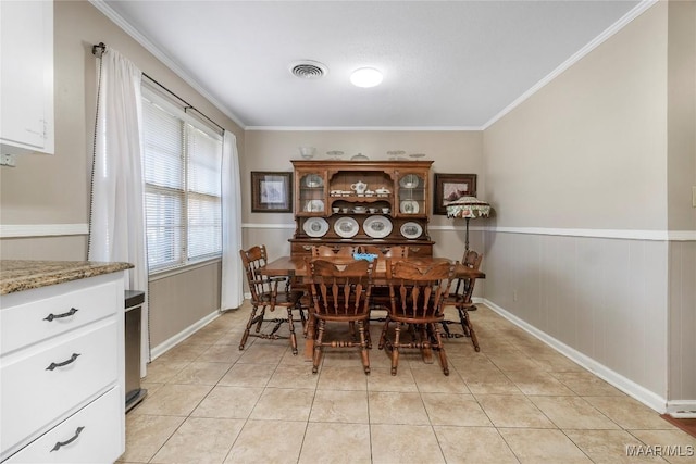 dining room featuring crown molding, light tile patterned flooring, and visible vents