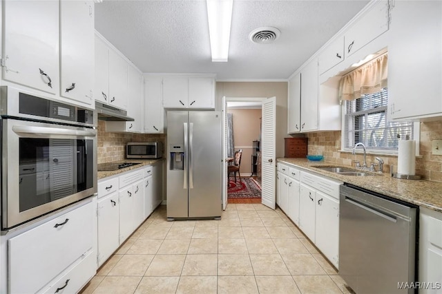 kitchen featuring visible vents, under cabinet range hood, a sink, appliances with stainless steel finishes, and light tile patterned floors