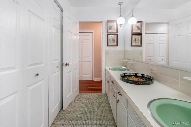 bathroom featuring decorative backsplash, double vanity, a closet, and a sink