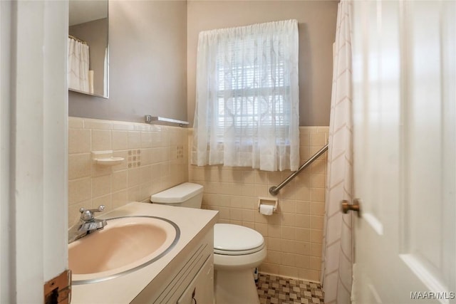 full bathroom with vanity, tile walls, toilet, and a wainscoted wall