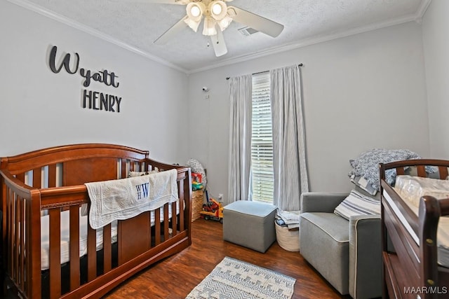 bedroom with a crib, a textured ceiling, wood finished floors, crown molding, and ceiling fan