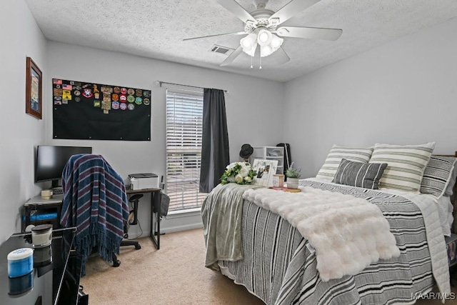 bedroom with ceiling fan, visible vents, carpet floors, and a textured ceiling