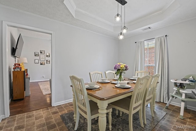 dining space with visible vents, baseboards, a tray ceiling, ornamental molding, and a textured ceiling