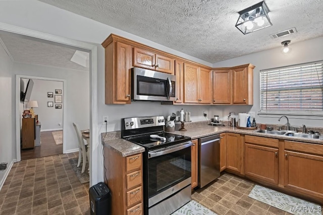 kitchen with a sink, visible vents, a textured ceiling, and appliances with stainless steel finishes