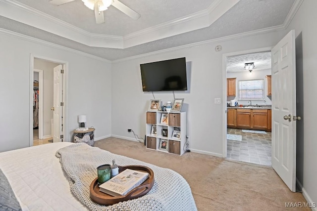 bedroom with a sink, a tray ceiling, light colored carpet, and a textured ceiling