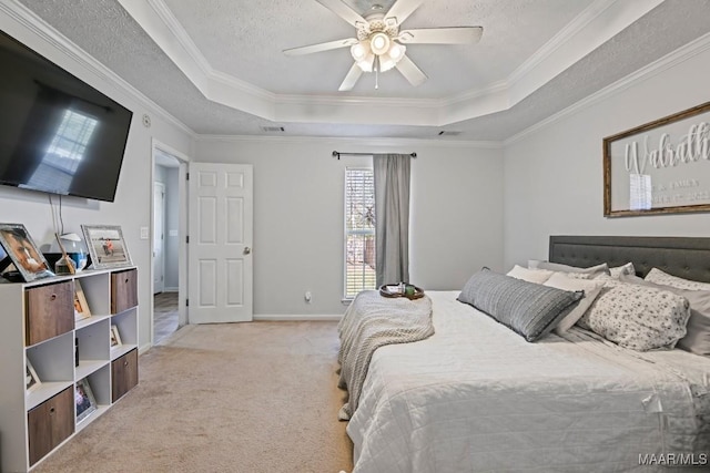 bedroom featuring light carpet, a textured ceiling, a tray ceiling, and ornamental molding