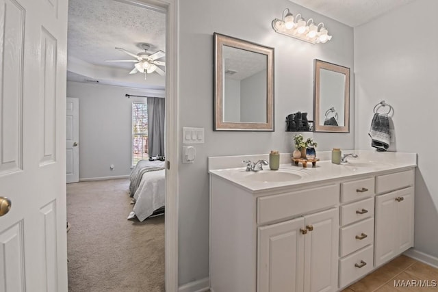 full bath with double vanity, a textured ceiling, a ceiling fan, and a sink