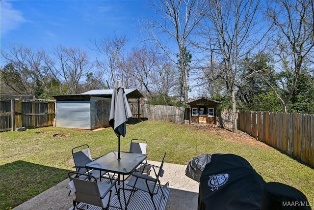 view of yard featuring an outbuilding, a fenced backyard, outdoor dining space, and a patio area