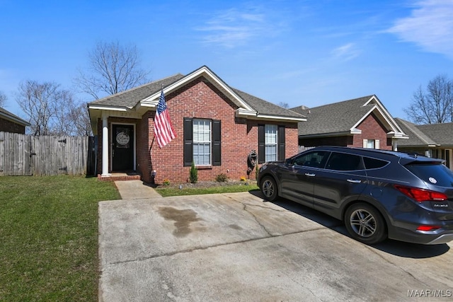 view of front facade featuring a front lawn, fence, brick siding, and roof with shingles