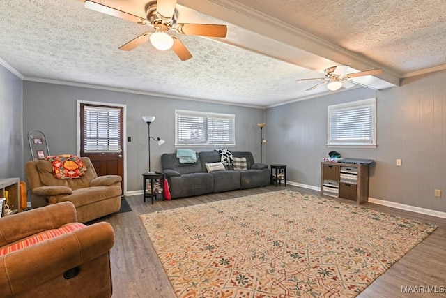 living area with baseboards, ceiling fan, ornamental molding, wood finished floors, and a textured ceiling