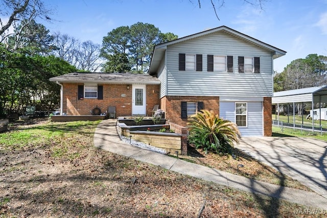 split level home featuring brick siding, a vegetable garden, a detached carport, and concrete driveway