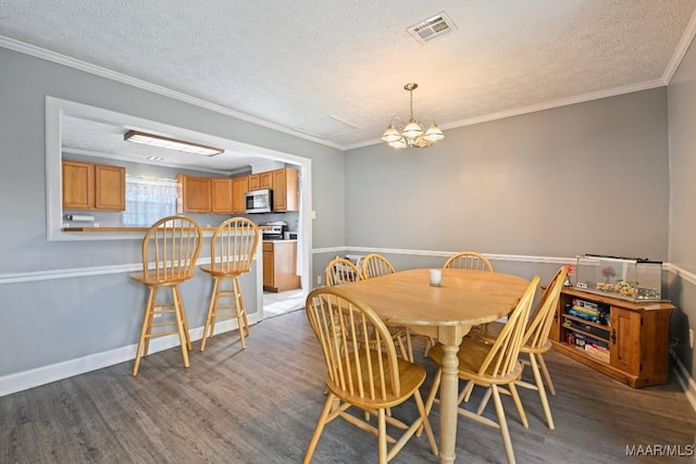 dining room with visible vents, a textured ceiling, wood finished floors, and crown molding