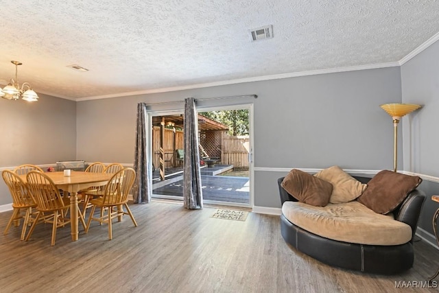 dining area featuring an inviting chandelier, wood finished floors, visible vents, and ornamental molding