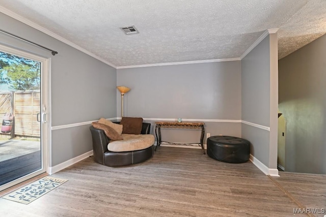 sitting room featuring crown molding, wood finished floors, visible vents, and baseboards