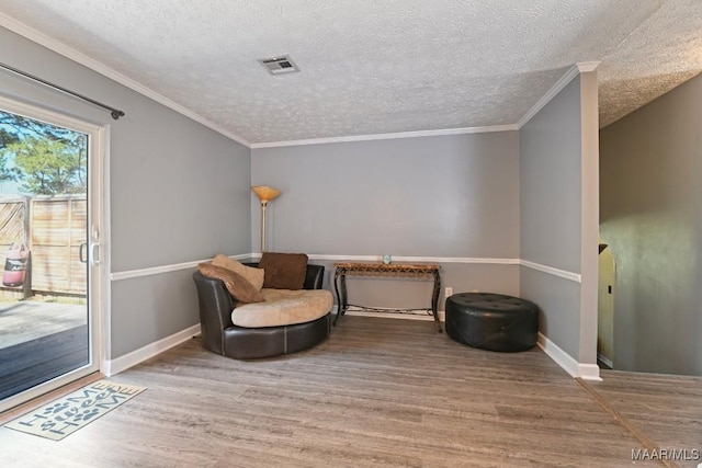 sitting room with visible vents, crown molding, baseboards, wood finished floors, and a textured ceiling