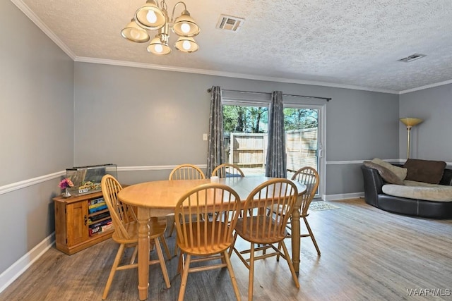 dining space with a chandelier, visible vents, baseboards, and wood finished floors