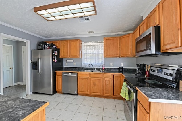 kitchen with dark countertops, visible vents, crown molding, stainless steel appliances, and a sink