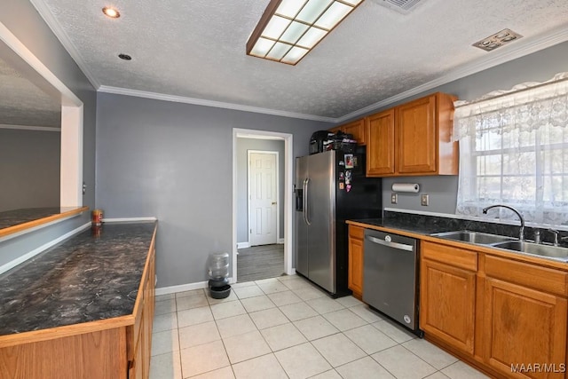 kitchen with a sink, crown molding, appliances with stainless steel finishes, dark countertops, and brown cabinets