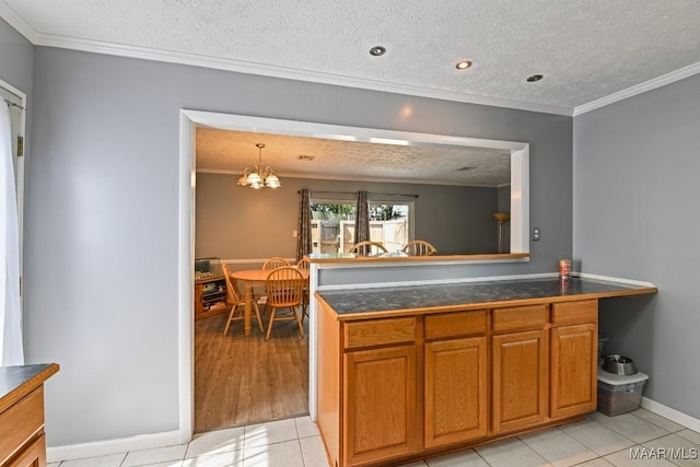 kitchen with brown cabinets, a textured ceiling, a chandelier, and crown molding