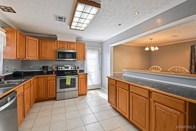 kitchen with a sink, stainless steel appliances, dark countertops, and visible vents
