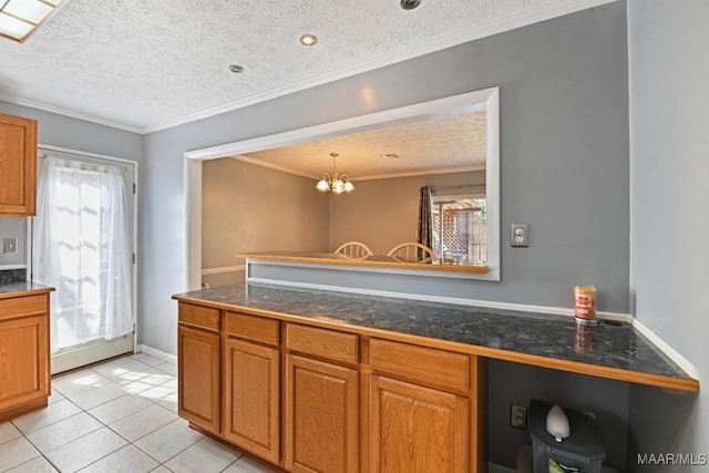 kitchen with light tile patterned floors, brown cabinetry, crown molding, a textured ceiling, and dark countertops