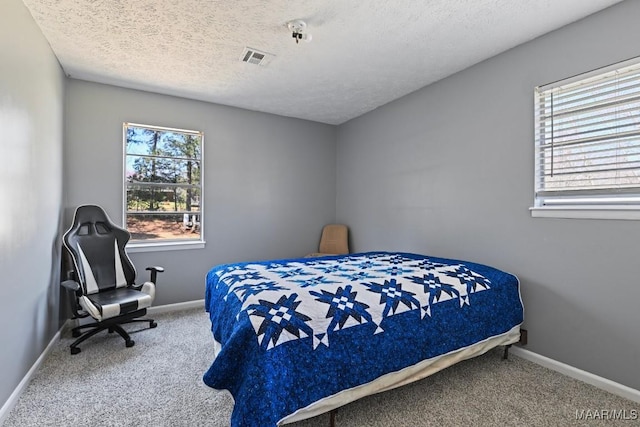 carpeted bedroom with baseboards, visible vents, and a textured ceiling