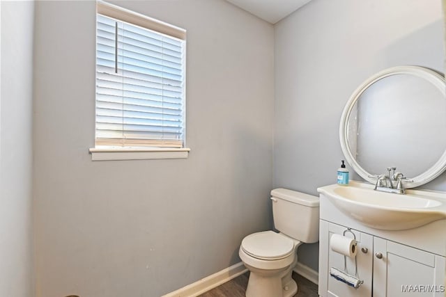 bathroom featuring baseboards, toilet, wood finished floors, and vanity