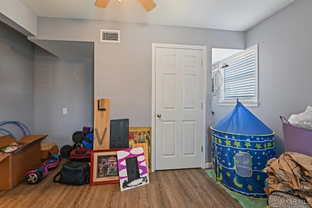 playroom with ceiling fan, visible vents, and wood finished floors