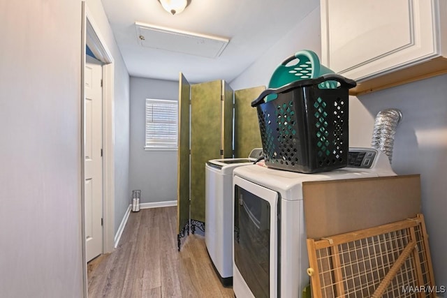 clothes washing area with baseboards, washer and clothes dryer, attic access, wood finished floors, and cabinet space