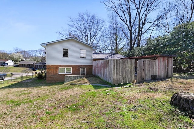 rear view of property with a yard, fence, and brick siding