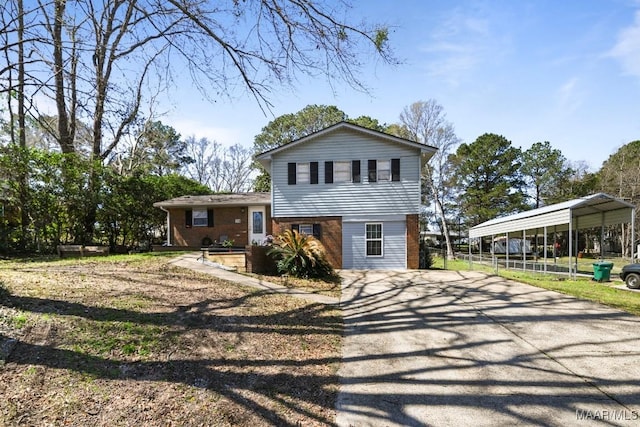 tri-level home with brick siding, driveway, and a detached carport