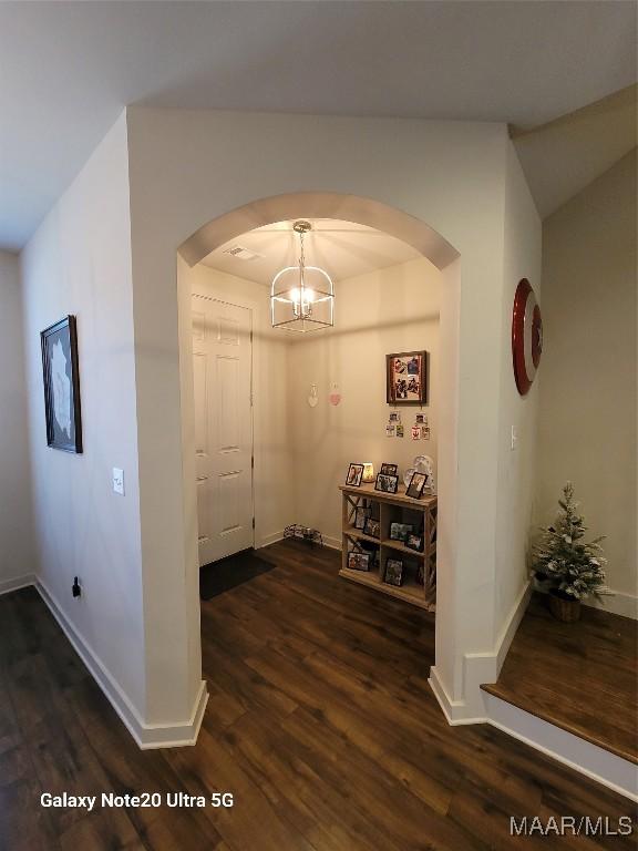 hall with arched walkways, dark wood-style floors, and baseboards