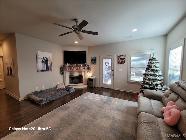 living room featuring a ceiling fan, dark wood-style floors, recessed lighting, and a fireplace with raised hearth